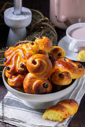 Obraz na płótnie Traditional saffron Swedish buns lussekatt in different shapes, served with cocoa on a wooden table. Buns for St. Lucia's Day. w salonie