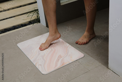 Modern bathtubBath matSpa-like settingRelaxationLuxury bathWhite bathrobeBath productsGreen plantsSerene bathroomIndoor garden bathtub person stepping out of a bathtub onto a bath mat. photo