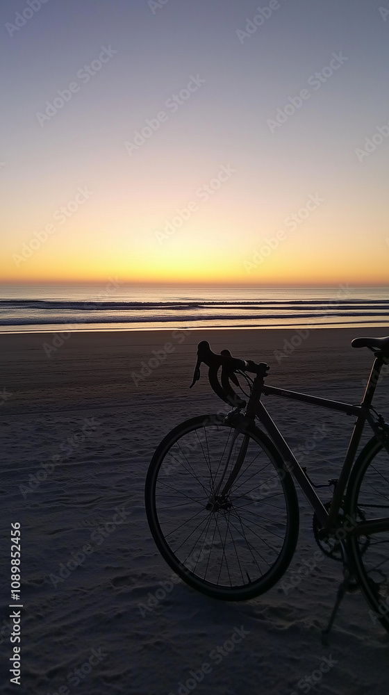 Fototapeta premium Bicycle on sandy beach at sunrise with ocean view