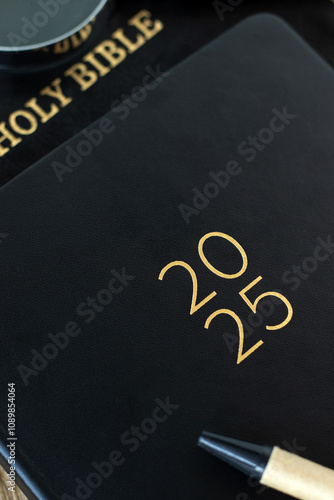 2025 calendar notebook with holy bible book. Close-up. Christian education and learning commitment, studying scripture, biblical concept. photo