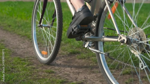 Child moving on bike in field. A view of young girl pedaling and moving along the green field in the village.
