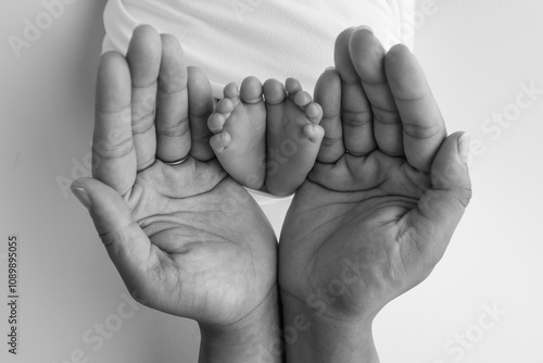 Black and white shade beautiful shape hands of mother, hold tiny newborn baby feet on black background with love, care, family safety and protection, child with premature birth concept or NICU care