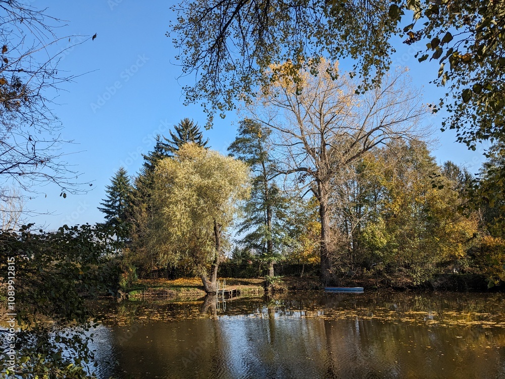 Fototapeta premium Vivid autumn panorama of a riverside pedestrian path near Pisarky in Brno, Czech Republic, with colorful foliage and calm natural surroundings.