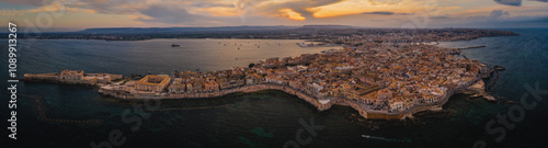 Siracusa, Ortigia Island from the air at sunset, Sicily, Italy. Isola di Ortigia, coast of Ortigia island at city of Syracuse, Sicily, Italy. Aerial view. June 2023