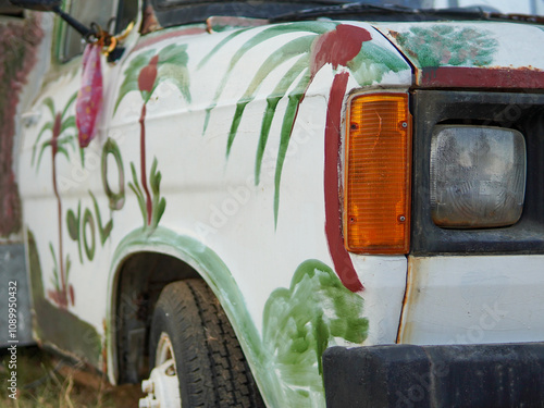 A unique van adorned with vibrant palm tree designs is parked in a sunny spot in Thassos, Greece. The playful artwork features the word Yolo, adding character to the vehicle. photo