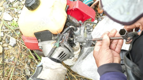 Male hands are using a screwdriver to repair a lawnmower. photo