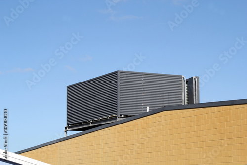 Large air conditioning unit on the roof of a building against a blue sky background