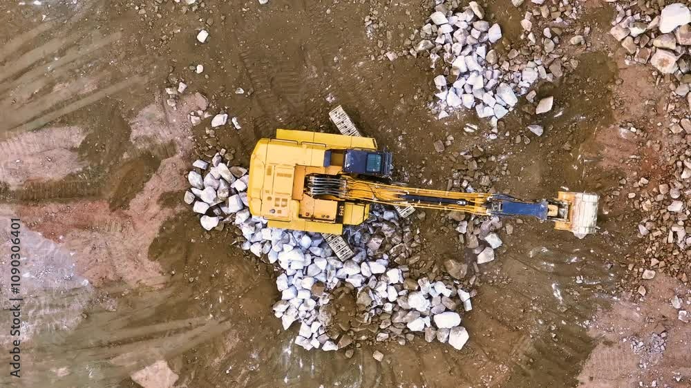 Excavator works to remove rocks at construction site in daylight Excavator works to remove rocks at construction site in daylight