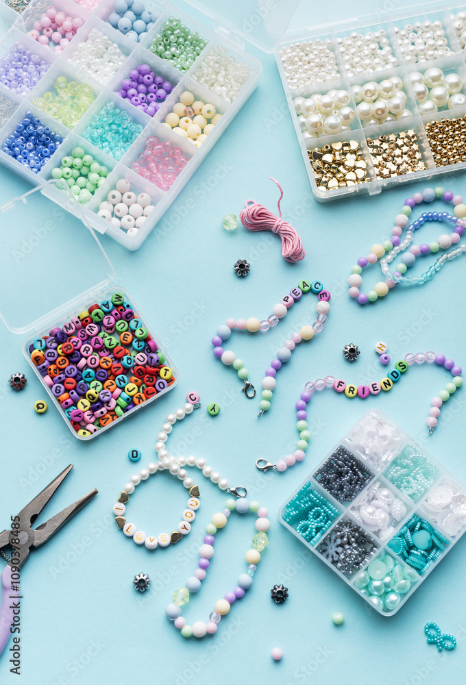 Colorful assortment of beads and jewelry-making tools on a blue surface with completed bracelets