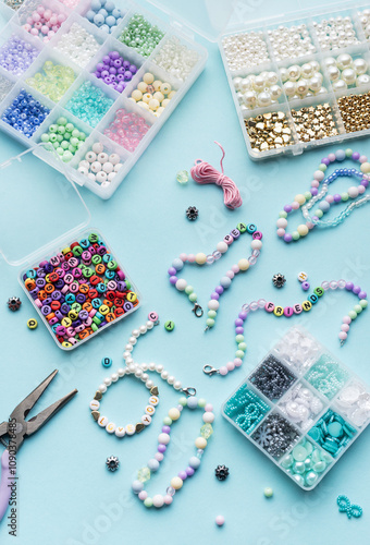 Obraz na płótnie Colorful assortment of beads and jewelry-making tools on a blue surface with completed bracelets w salonie