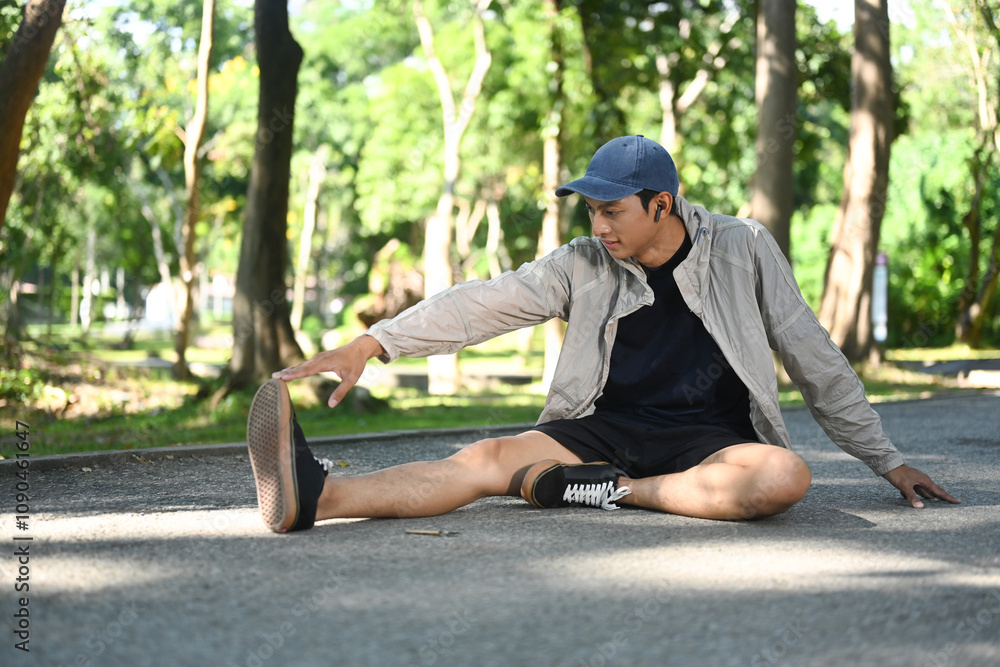Obraz premium Young sporty man stretching outdoors before running in nature during sunny summer day