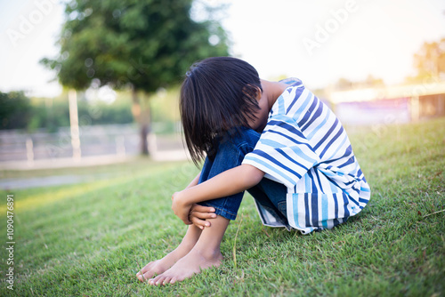 A sad little girl sitting alone outside photo