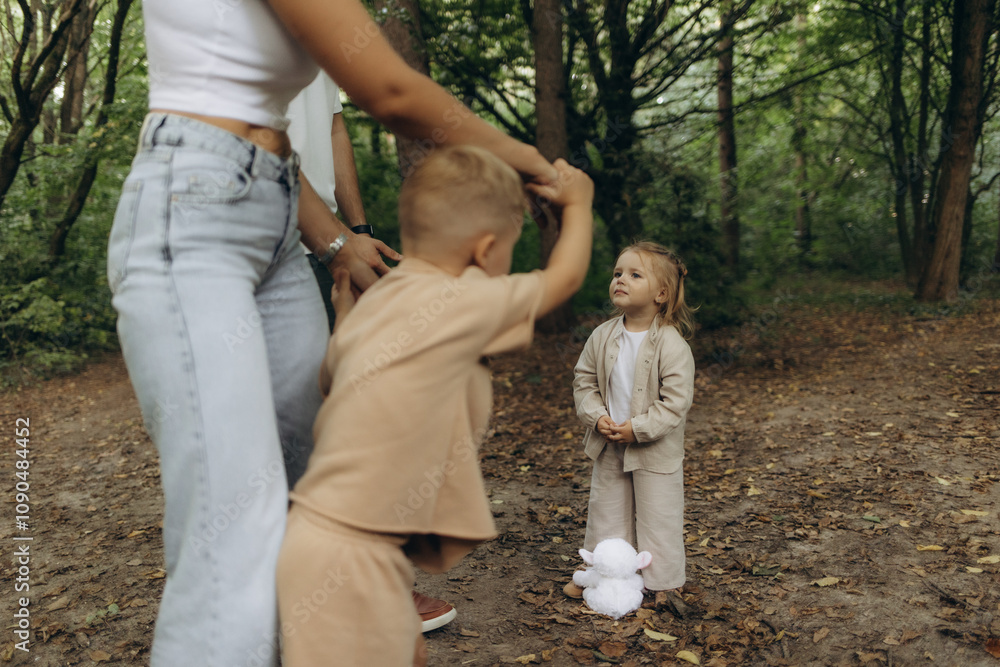 Fototapeta premium A little girl looks at her mother and brother