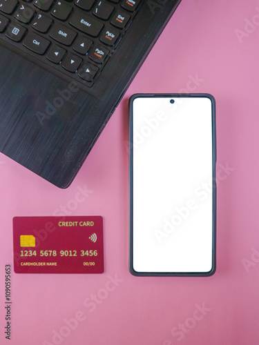 Credit cards, smartphone with blank screen and laptop on a pink background, representing technology and finance photo