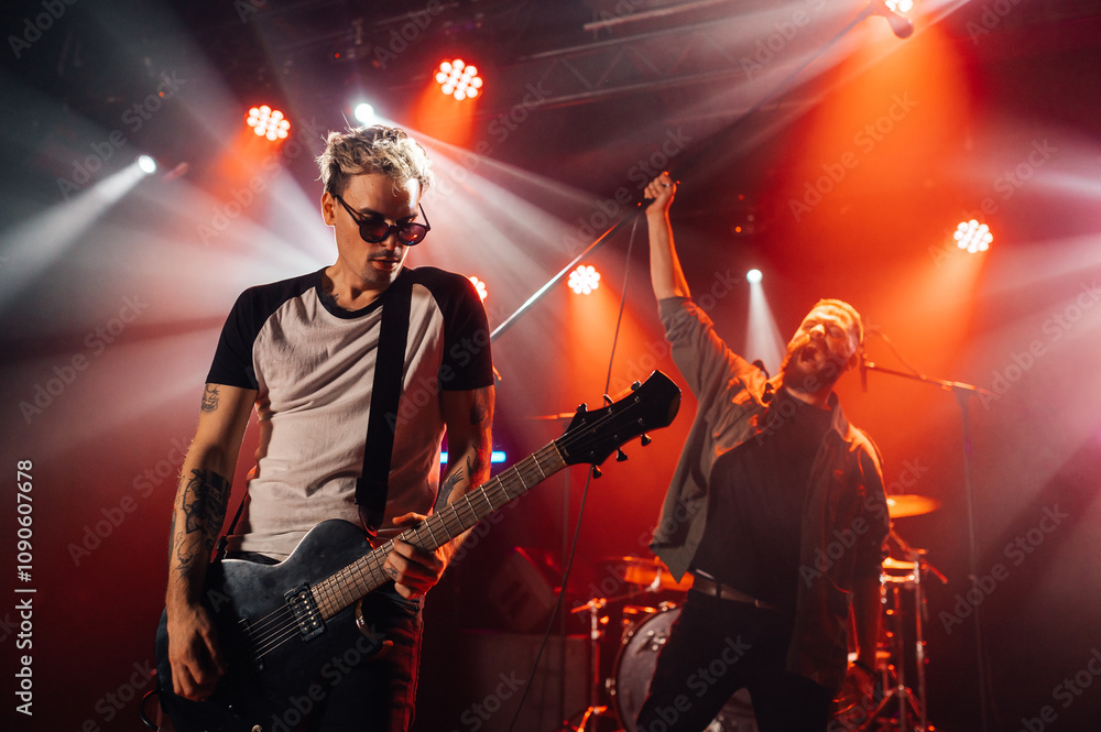 Obraz premium Rock band performing live on stage with energetic singer and guitarist