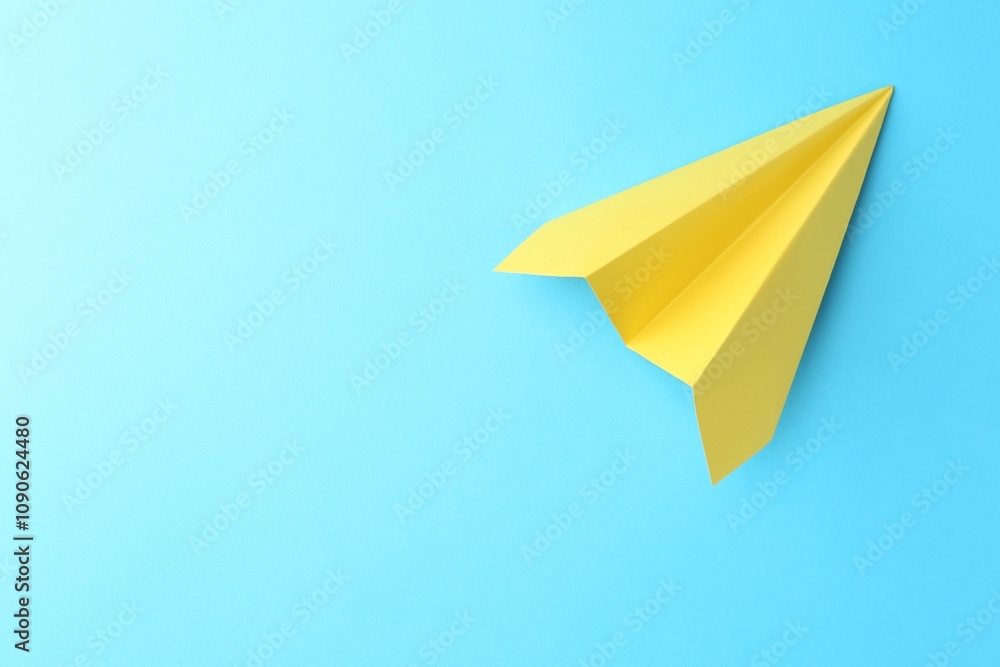 One handmade yellow paper plane on light blue background, top view. Space for text One handmade yellow paper plane on light blue background, top view. Space for text