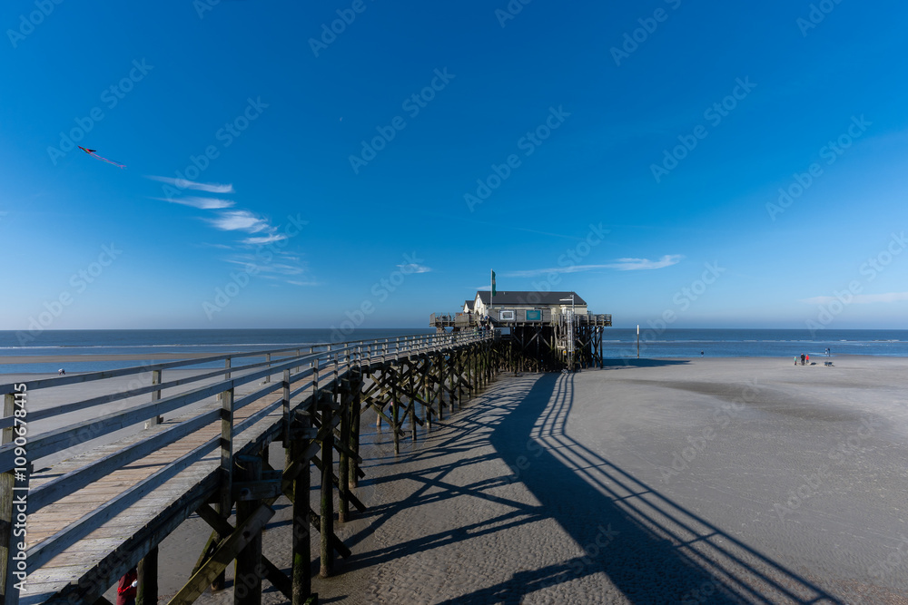 Fototapeta premium Laufsteg mit Pfahlbau am Strand von Sankt Peter Ording.