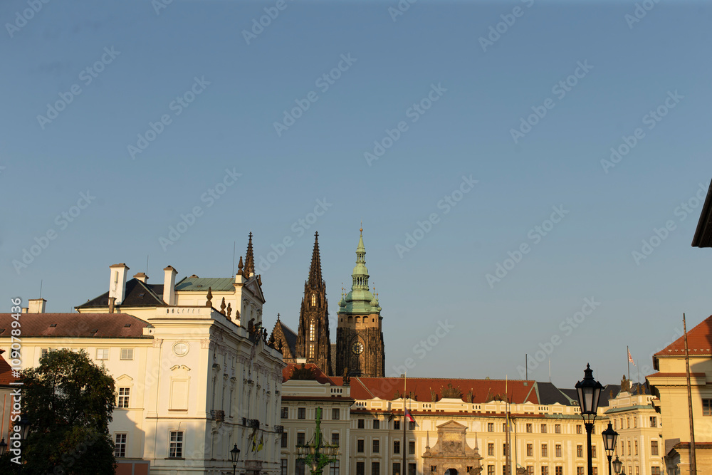 Fototapeta premium The iconic towers of Prague Castle and the magnificent St. Vitus Cathedral stand proudly against a clear blue sky in the beautiful city of Prague, located in the Czech Republic