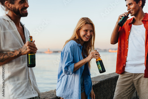 Friends enjoying beers by the waterside at sunset gathering