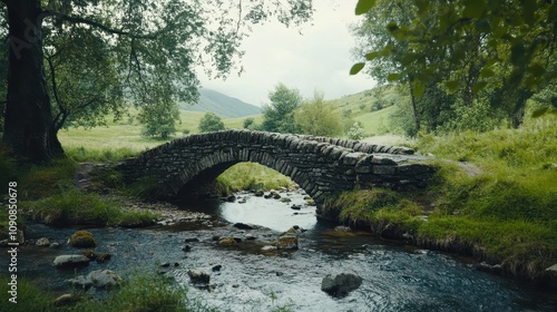 A small stone bridge crossing over a babbling brook in a countryside scene. photo