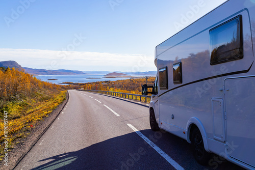 Motorhome driving on a scenic road in Kiruna, Sweden, with autumn foliage and beautiful lake views. photo