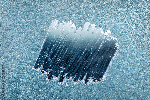 Frosted Window With a Clear Patch Revealing an Icy Blue Background During a Cold Winter Morning