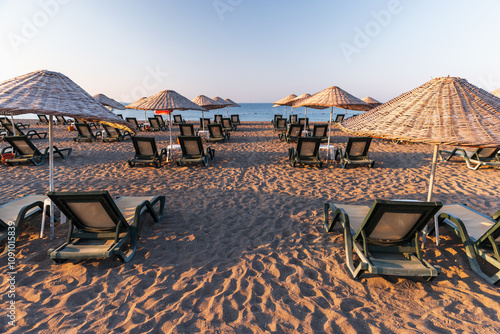 Fototapeta Naklejka Na Ścianę i Meble -  Straw umbrellas and vacant sun lounges are at Sarigerme beach