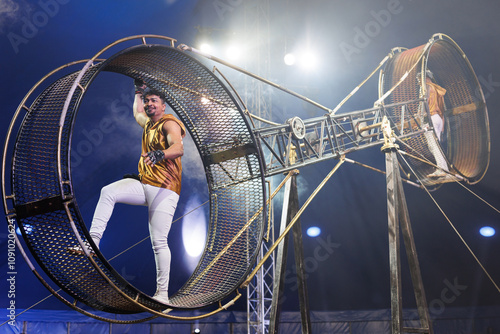 Brave male acrobats in the rotating wheel of death perform under the dome of the circus. photo