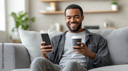 A man enjoying coffee while using his smartphone on a cozy couch.