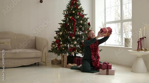 A happy red-bearded young man unpacking Christmas presents at home by the Christmas tree.New Year and Christmas concept.