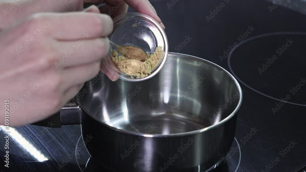 Adding ground ginger to a saucepan for mulled wine preparation, festive cooking process Adding ground ginger to a saucepan for mulled wine preparation, festive cooking process