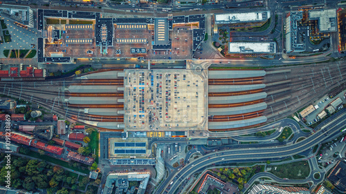 Fototapeta Naklejka Na Ścianę i Meble -  Aerial view of large parking lot with cars in Krakow, Poland. Railway station with trains, rails from below.