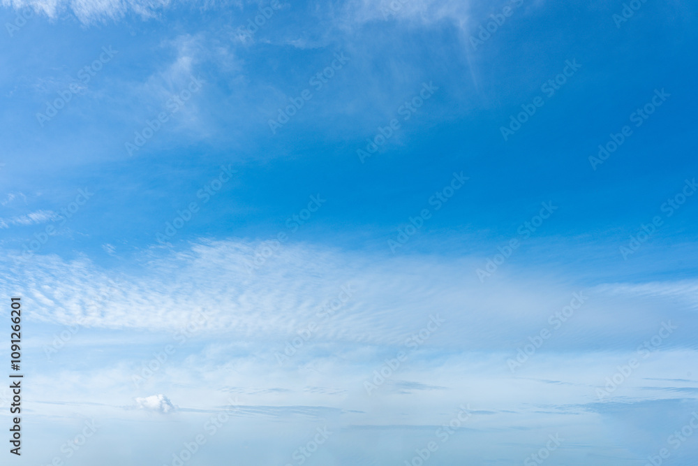 Fototapeta premium Fluffy white clouds drift across a clear blue sky