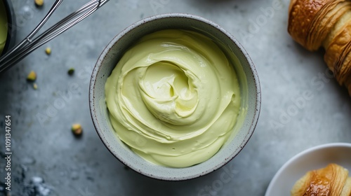 A Bowl of a delicious Pistachio Cream surrounded by Croissants and whole Pistachios. Perfect for Dessert and Breakfast themed menug suggestions. Trend Dessert.
