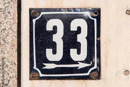 Weathered enameled plate of street address with number 33