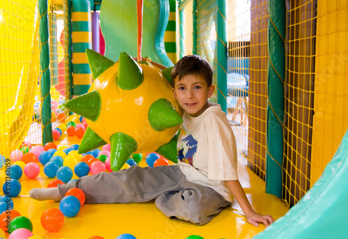 Cute cheerful boy playing from in entertainment center. photo