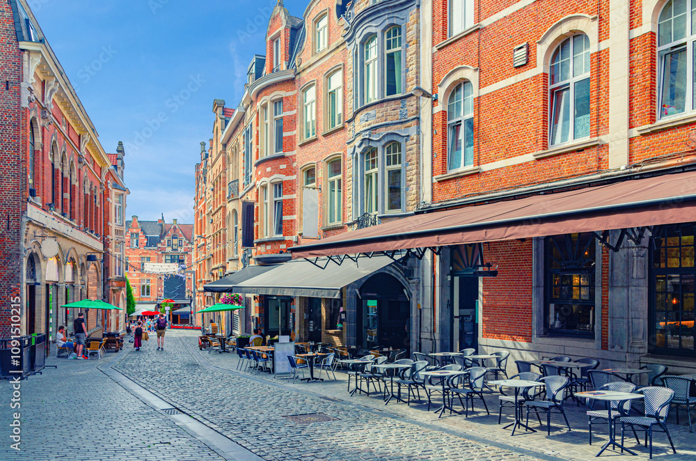 Fototapeta premium Pedestrian street with restaurants and cafes in old town Leuven historical city center, typical european street with tables and chairs of restaurant, Flemish Region, Flemish Brabant province, Belgium
