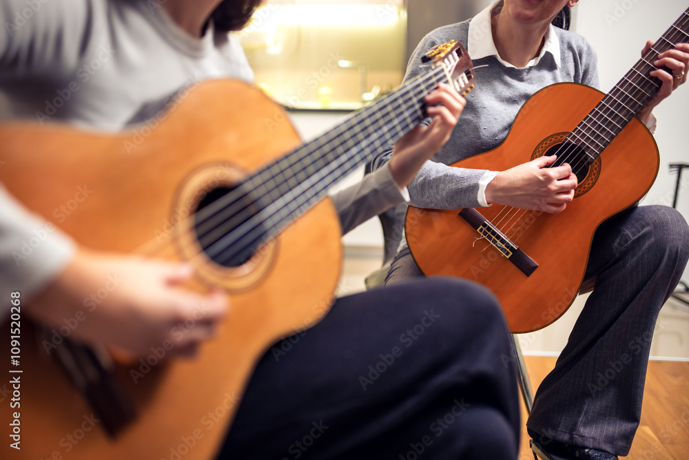 Obraz premium Mother and daughter playing guitar at home. A mother teaches her daughter to play the guitar.