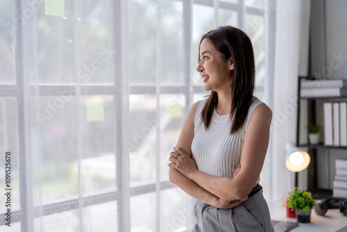 Free Download Young businesswoman smiling and looking through the window in office - GFXLoad