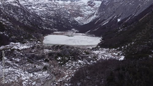 Aerial view of Laguna Esmeralda frozen in the mountains and forest in Ushuaia, Tierra del Fuego, Patagonia Argentina.
