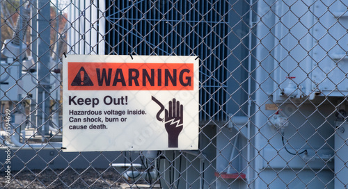 A WARNING sign saying KEEP OUT! posted on a chain link fence.