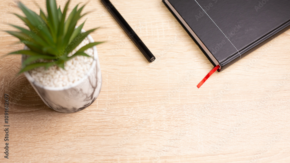 Fototapeta premium Notebook, pen and plant creating a relaxing workspace on wooden table