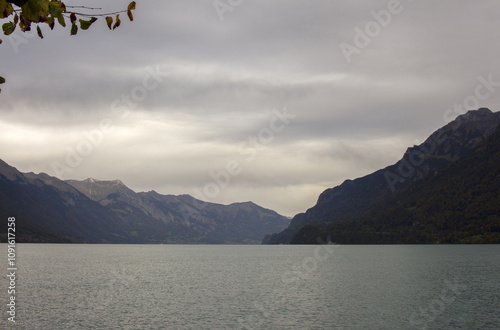 Landscape with a lake in Switzerland. Calm water, shore and mountains. Cloudy sky. Beauty in nature and travel
