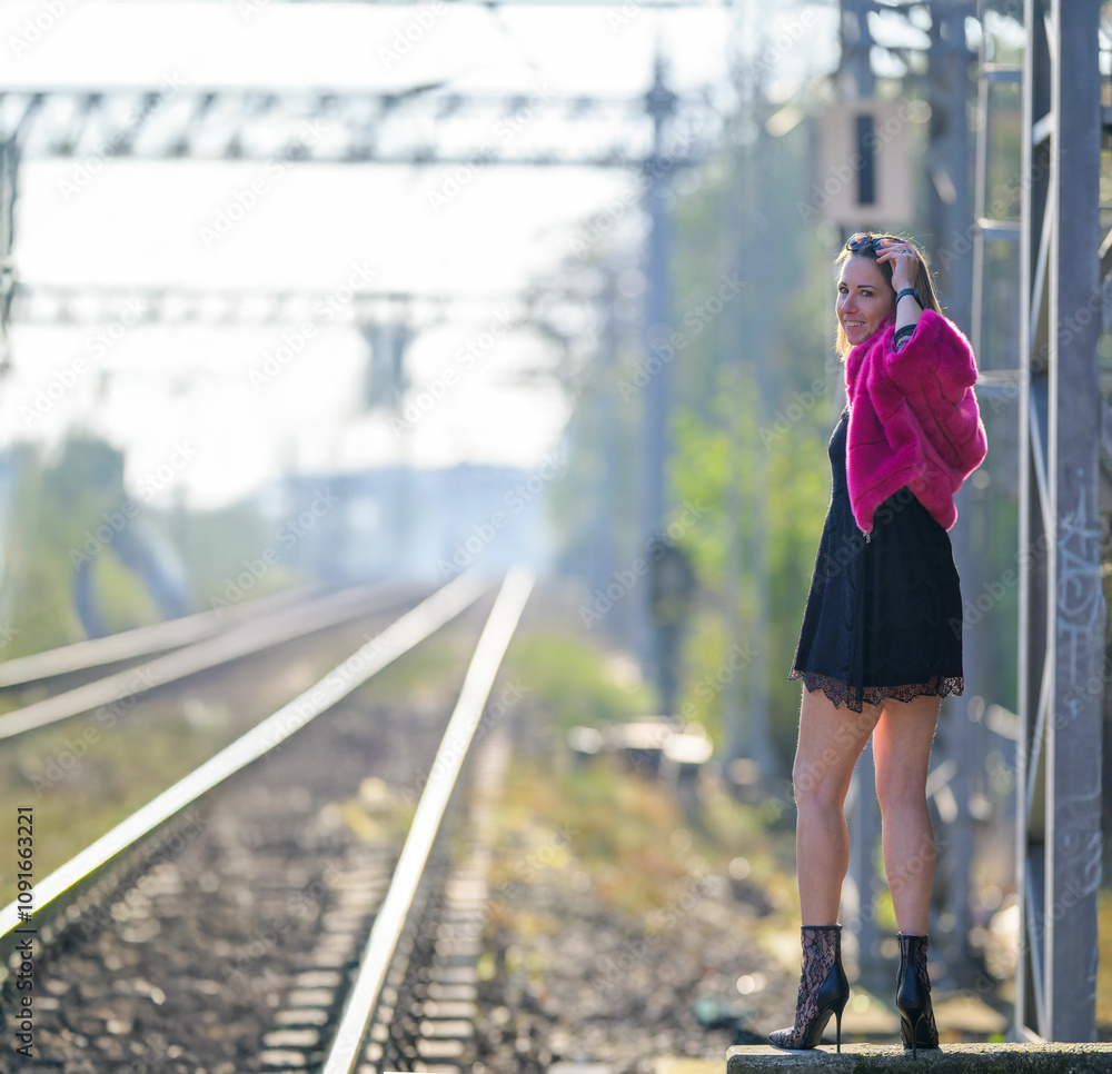 Obraz premium Bella donna posa vicino a fianco dei binari del treno