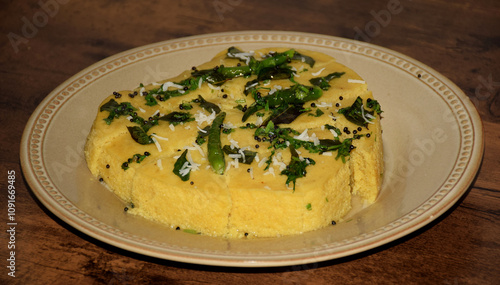 Side angle shot of Delicious Dhokla served on a bone china plate which is a yellow color sponge dish that is native to the Indian state of Gujarat 