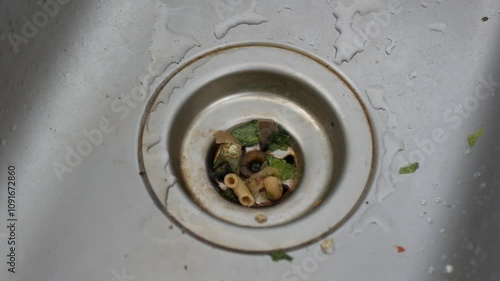 Dirty kitchen sink with food waste causing a clog.