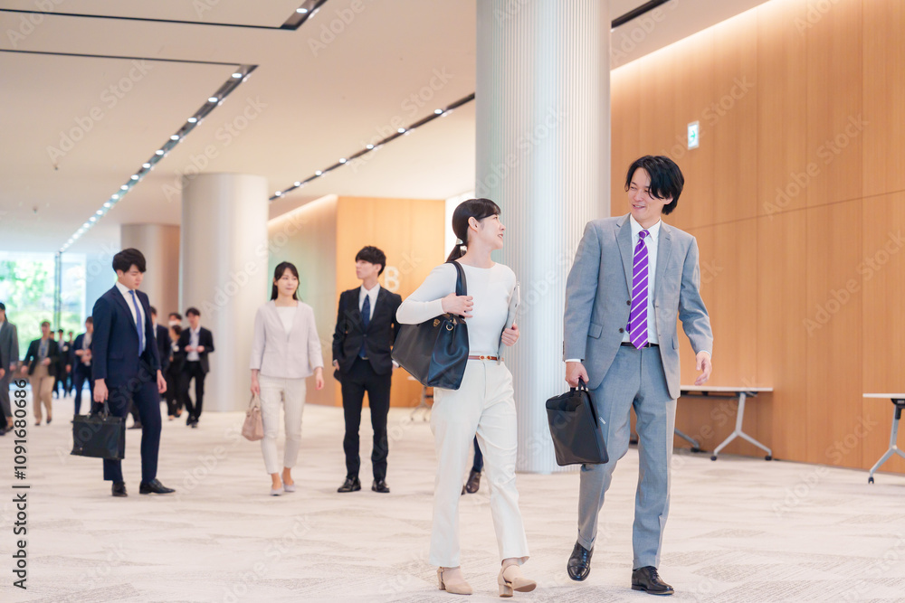 Obraz premium オフィスのホールで話しながら歩くビジネスパーソン