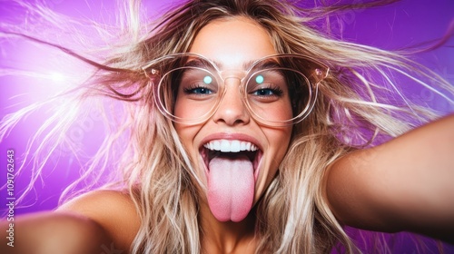 A woman with bright blonde hair and oversized glasses sticks her tongue out cheerfully, capturing a vibrant and playful selfie moment against a purple backdrop.