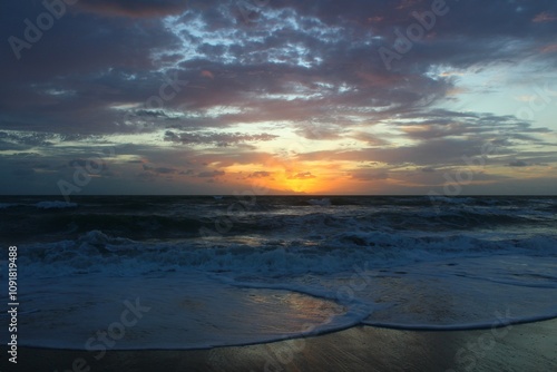 colorful sunrise on the beach with crashing waves and colors reflecting off ocean