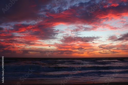 Pink clouds over ocean waves at sunrise on the beach 